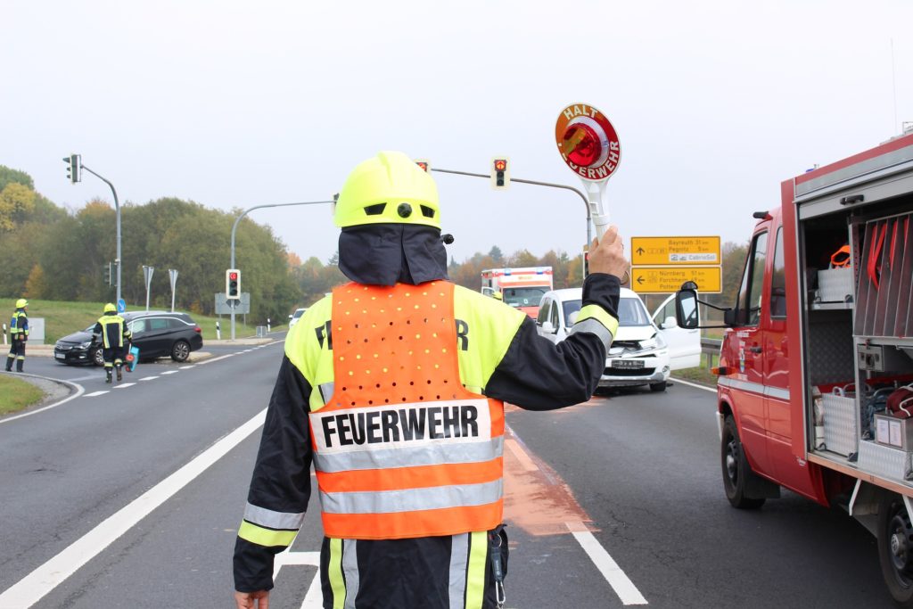 Feuerwehrmann in Warnweste mit Winkerkelle auf einer Straßenkreuzung