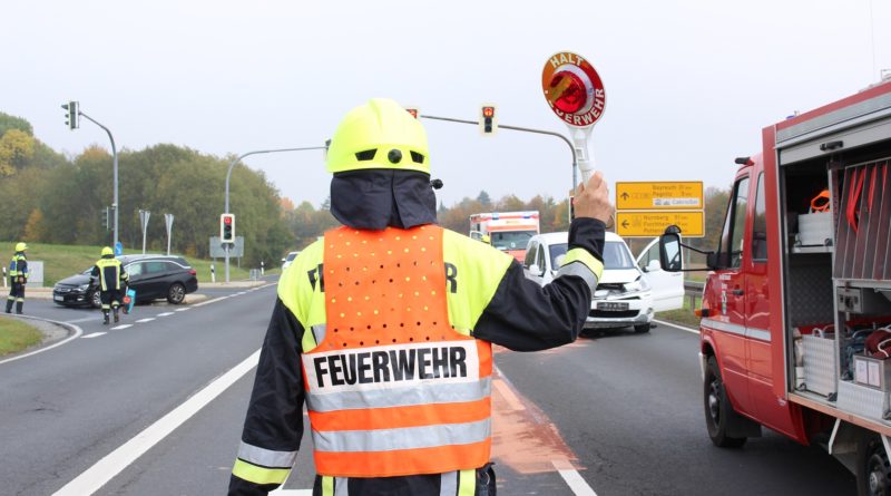 Feuerwehrmann in Warnweste mit Winkerkelle auf einer Straßenkreuzung