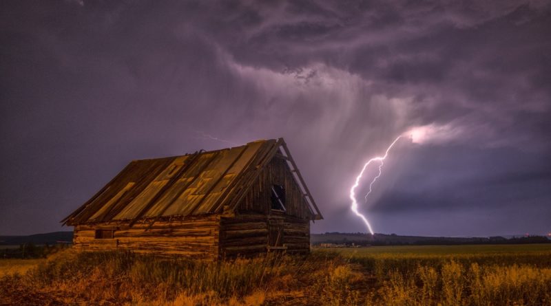 Blitzeinschlag am Horizont, vorne eine verfallene Holzhütte