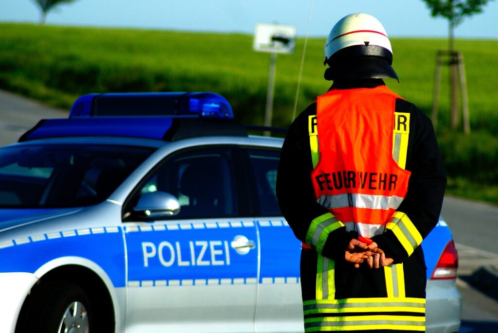 Feuerwehrmann mit Warnweste vor Polizeiauto